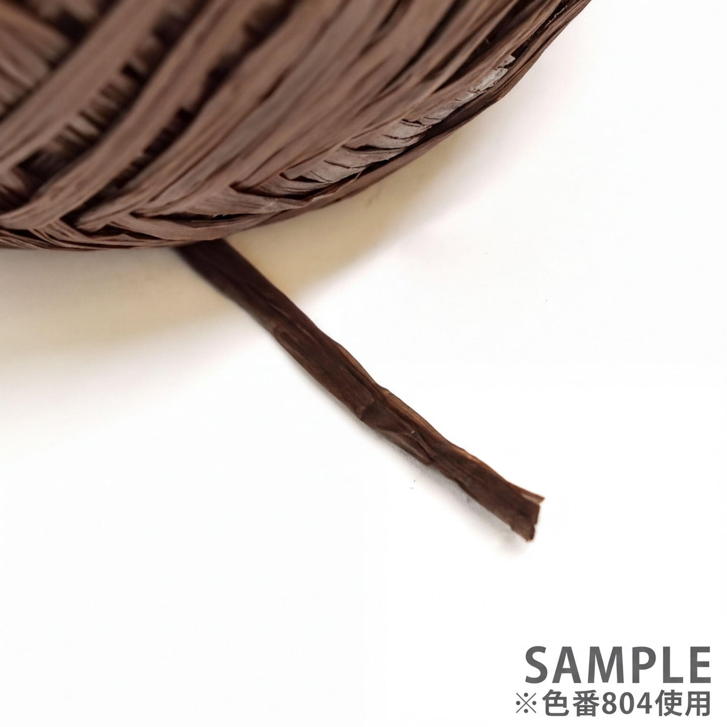 A close-up view of a brown, coiled object, possibly a piece of string or a similar material, resting on a white surface.