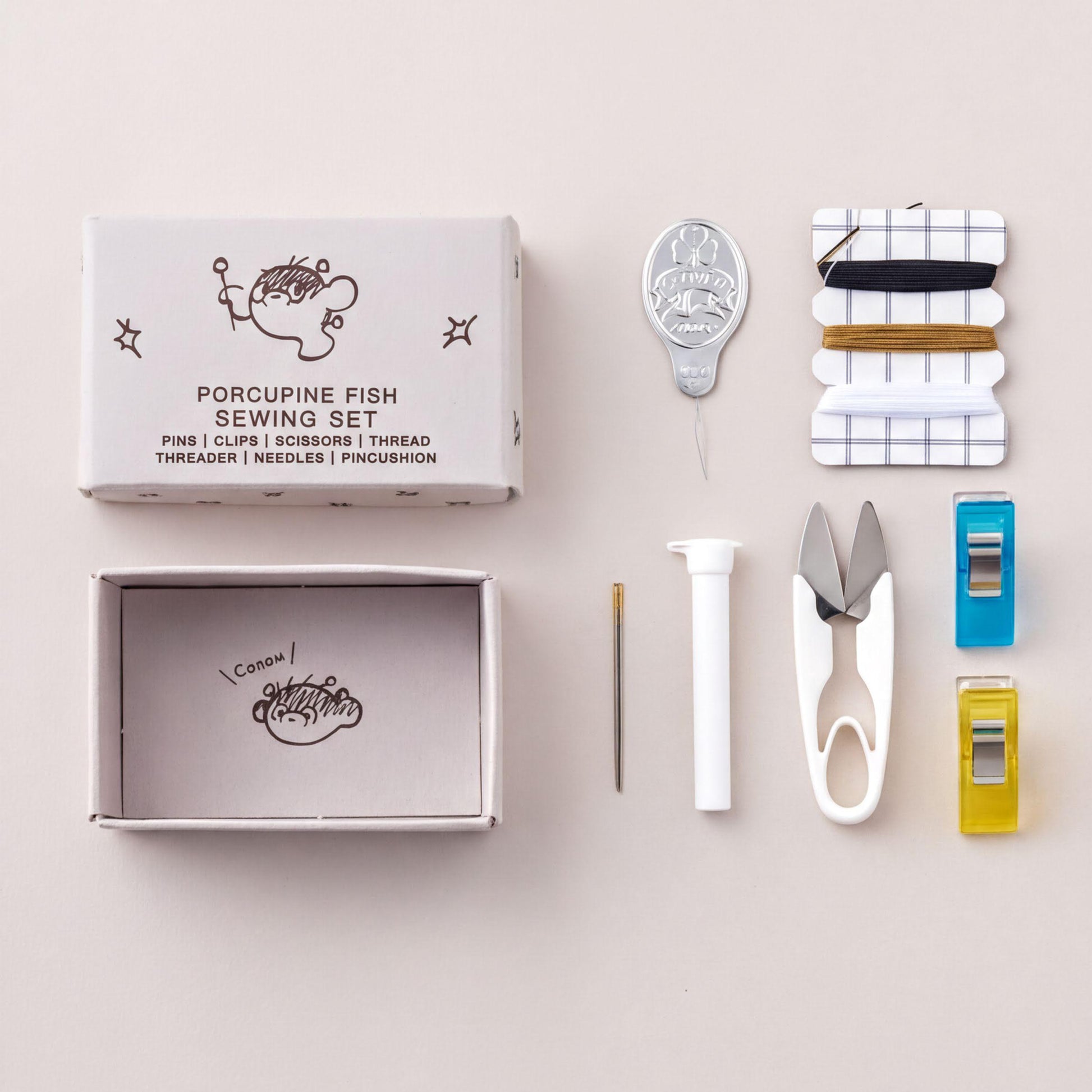 Porcupine Fish Sewing Set, Needles, Scissors, thread, threader, needles, pincushion, pin cushion, thimble, and scissors are arranged on a light background.