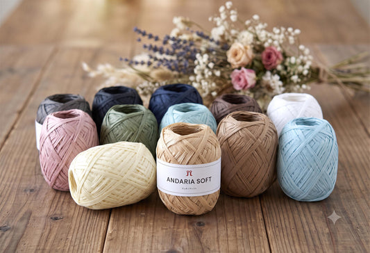 A collection of colorful spools of thread, including white, blue, green, and brown, arranged on a wooden surface alongside a bouquet of flowers.