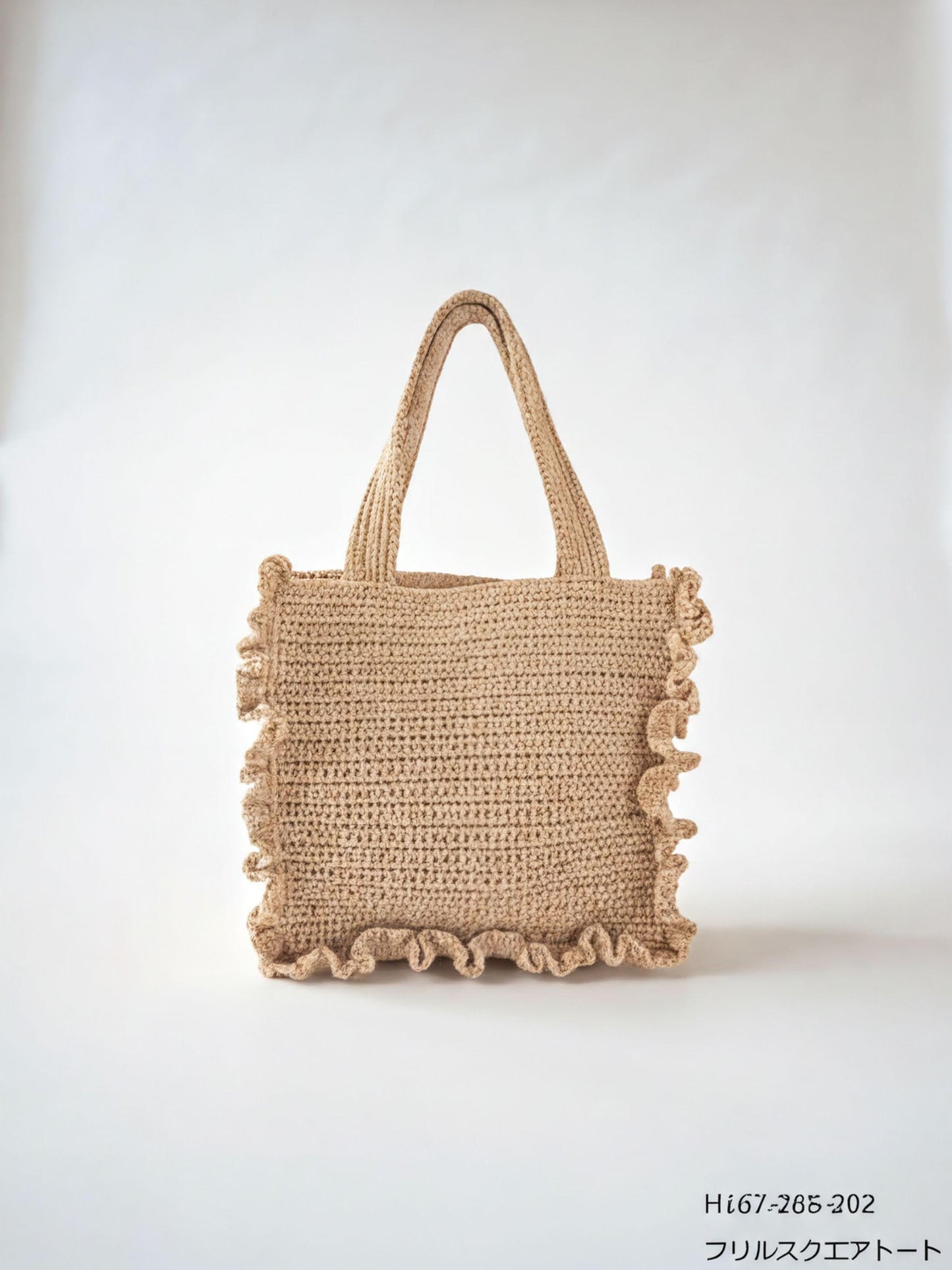 A beige crocheted tote bag with ruffled edges and handles, set against a plain white background.