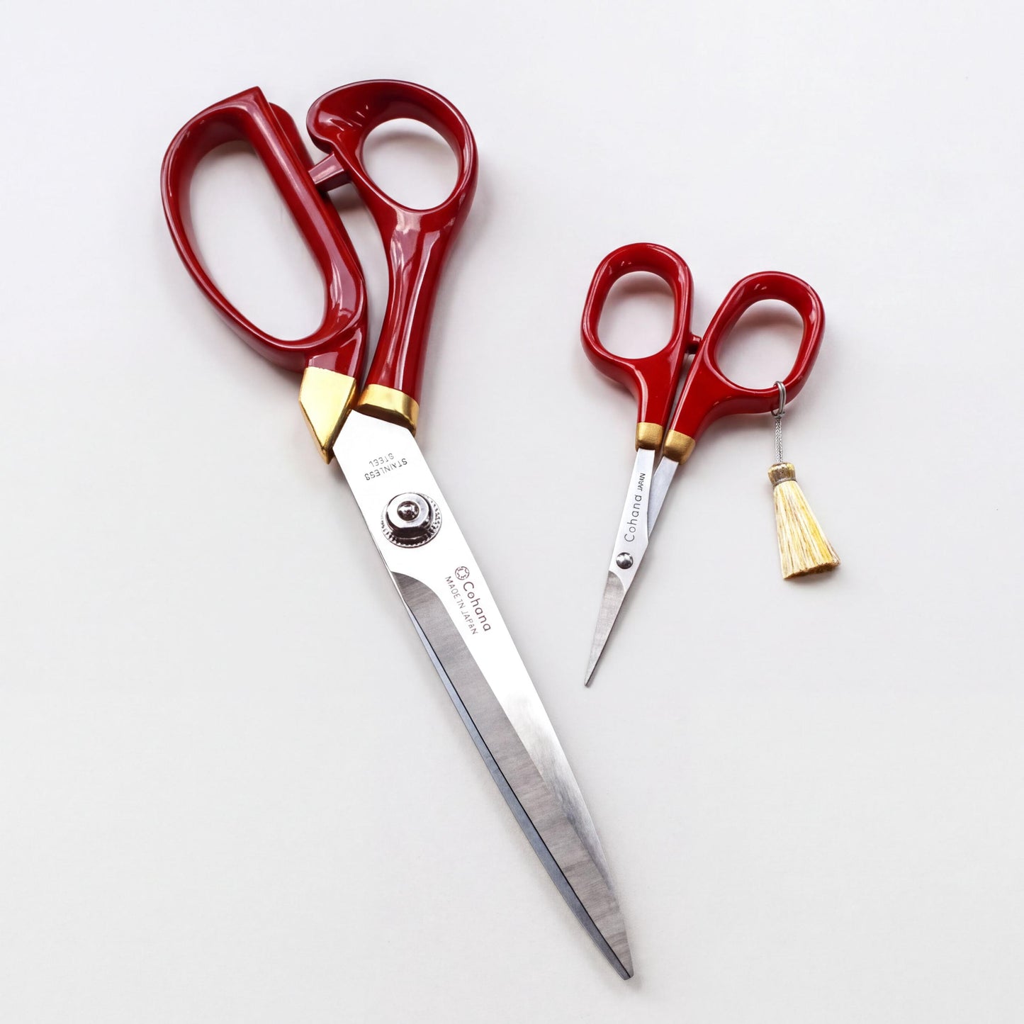 a pair of red scissors with gold accents, placed on a white background.