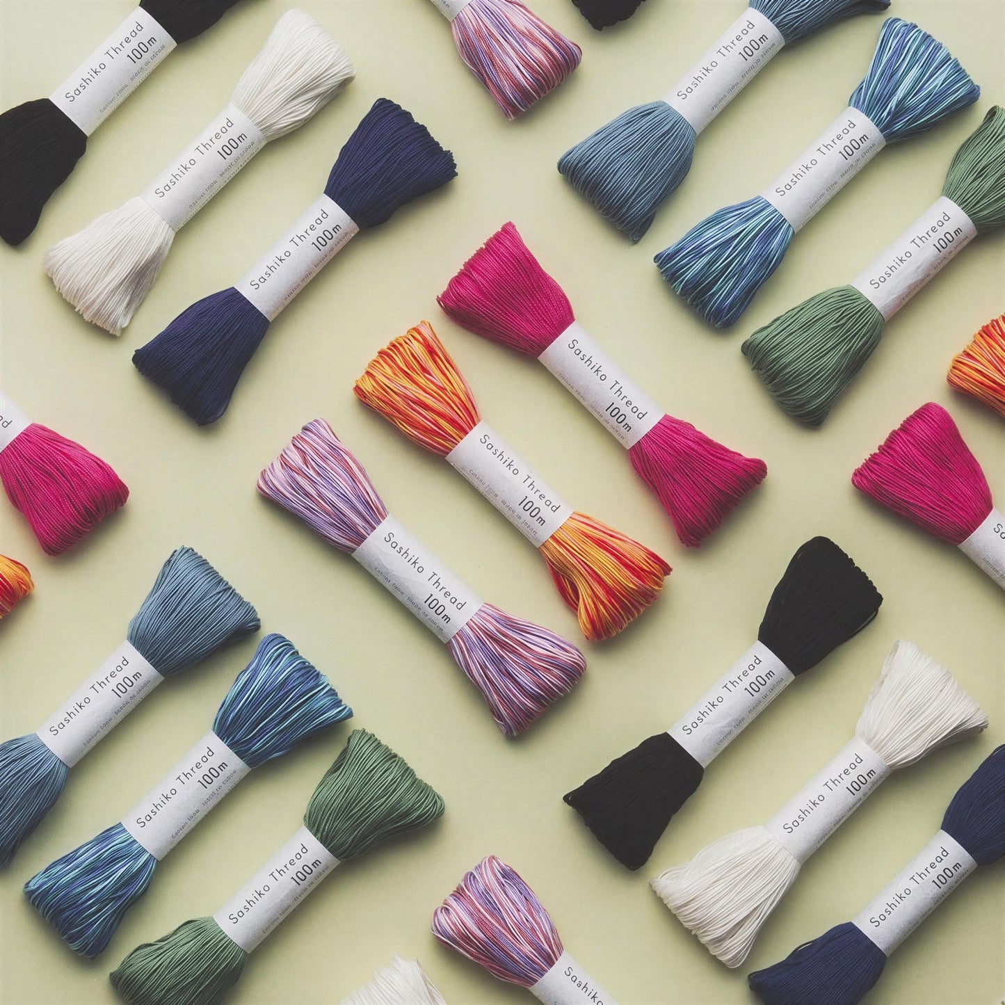 a collection of colorful spools of thread arranged in a grid-like pattern on a light green background.