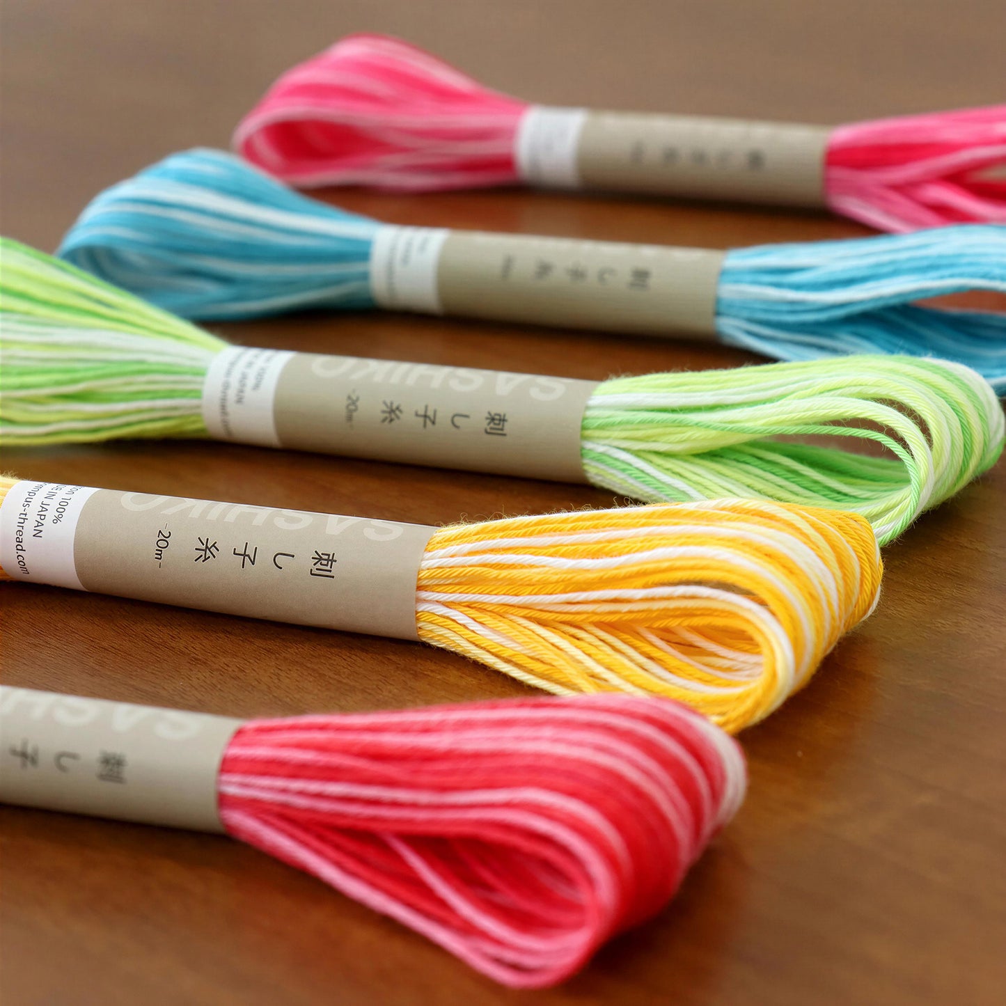 a collection of colorful spools of thread or yarn, each with a label indicating the color and possibly the brand or product information.