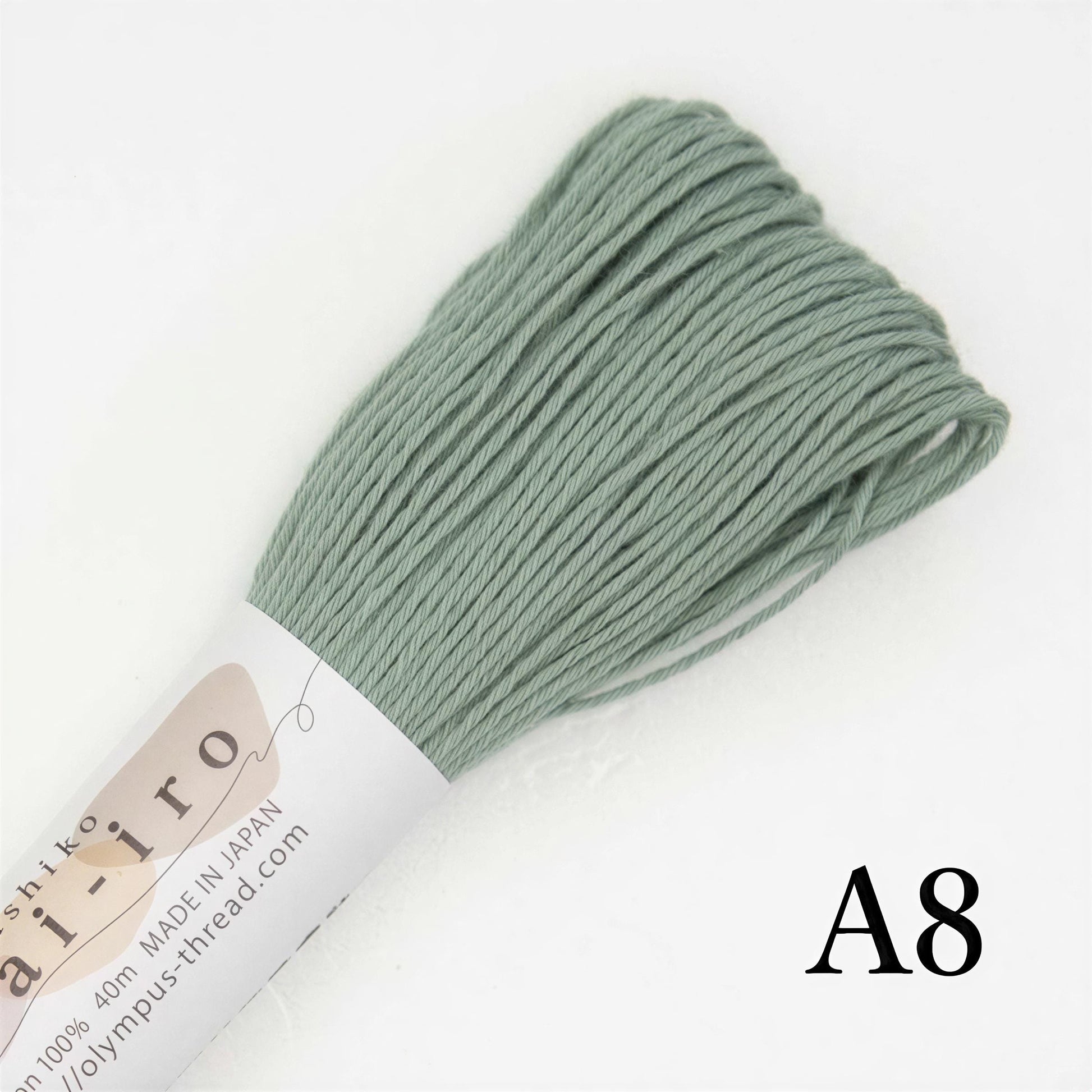 A spool of green thread is shown against a white background, with the text "A8" visible.