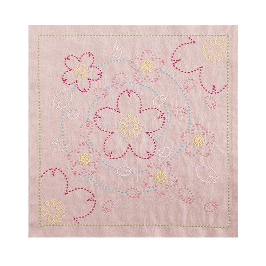 a square-shaped fabric with a floral design, including pink and yellow flowers and leaves. The design is created using a needle and thread technique, with the flowers and leaves appearing as small, intricate patterns.