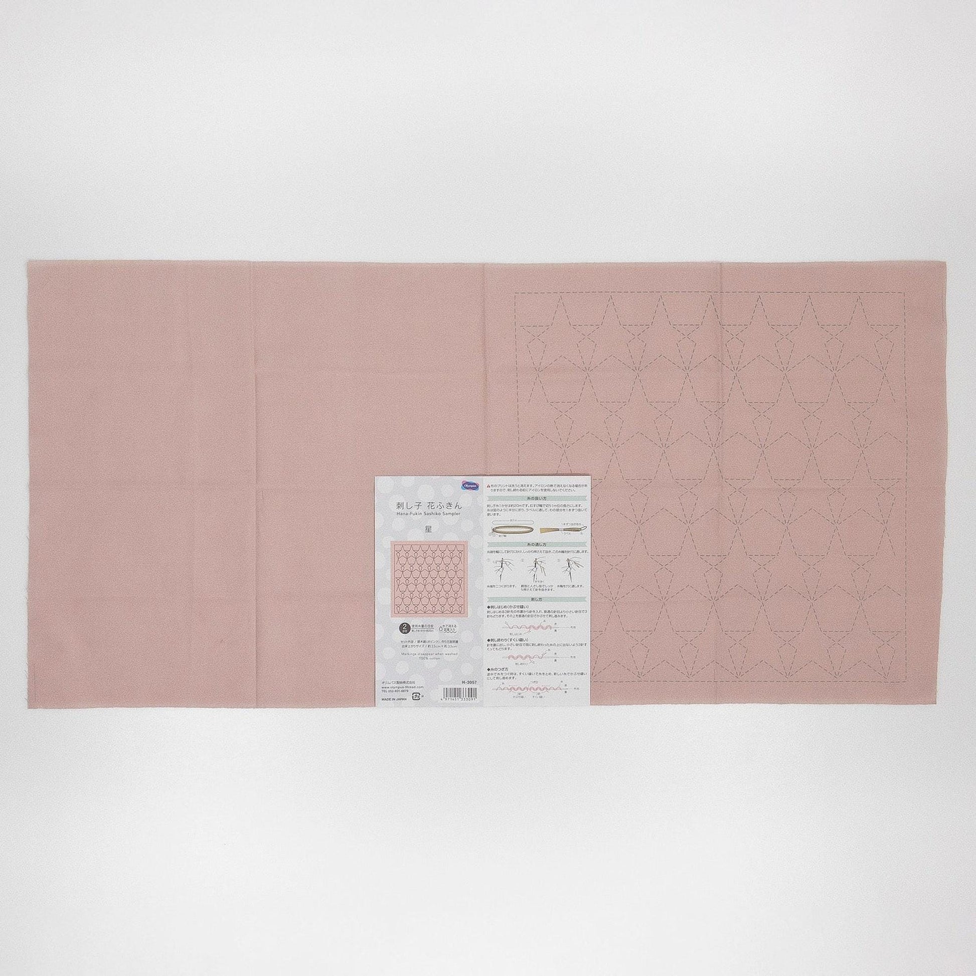 The image is a pink fabric with a pattern of small white dots or lines, and there is a printed paper with instructions or information about the fabric.