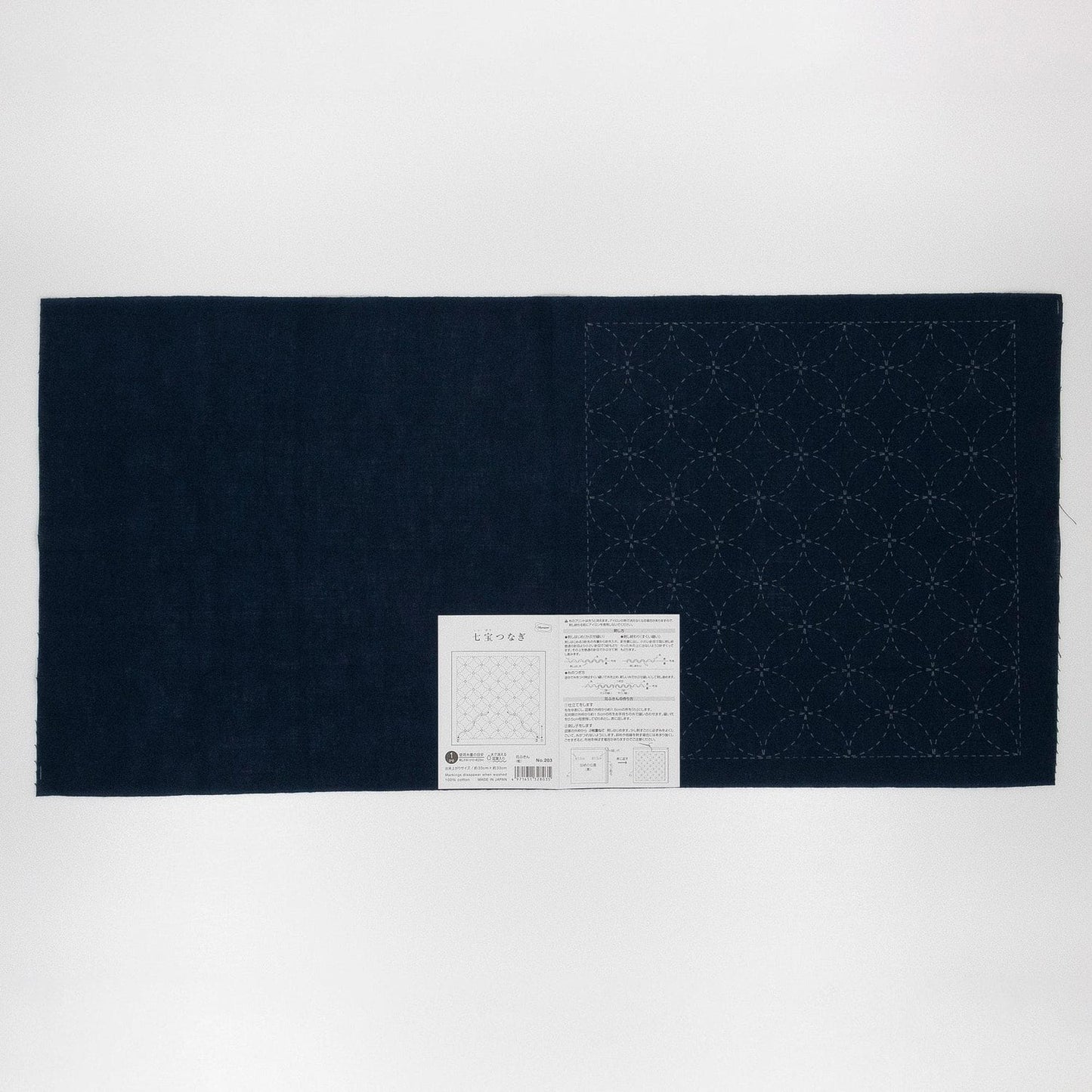 a dark blue fabric with a white label attached to it, which appears to be a piece of paper with instructions or information.