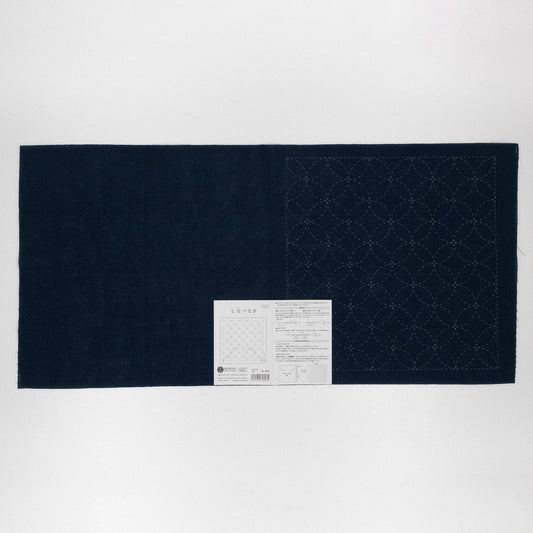 a dark blue fabric with a white label attached to it, which appears to be a piece of paper with instructions or information.