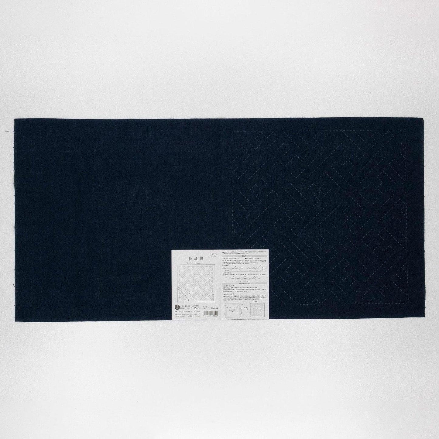 The image is a black and white photograph of a large piece of fabric with a white label attached to it.