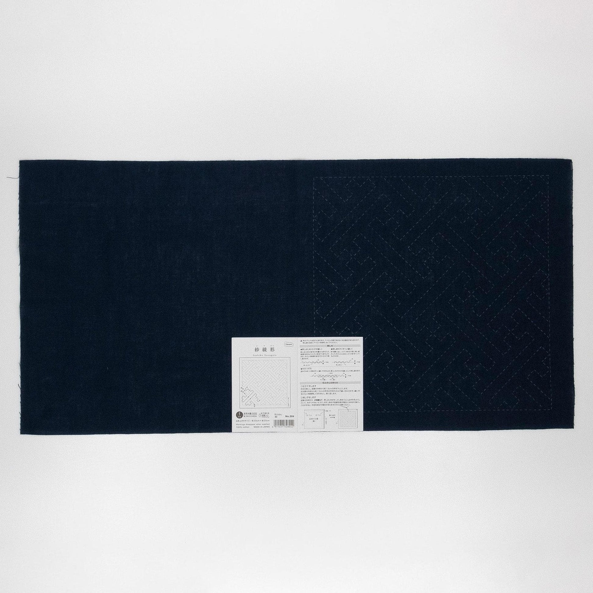 The image is a black and white photograph of a large piece of fabric with a white label attached to it.