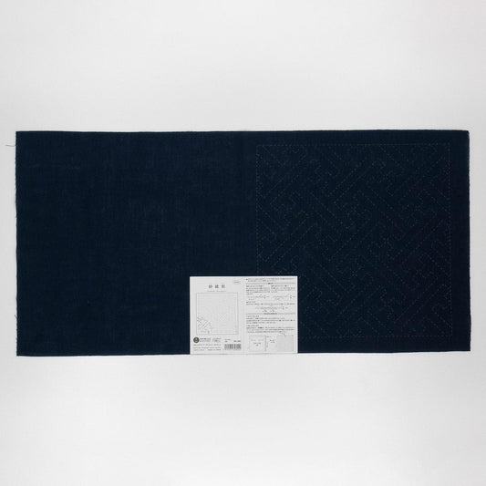 The image is a black and white photograph of a large piece of fabric with a white label attached to it.