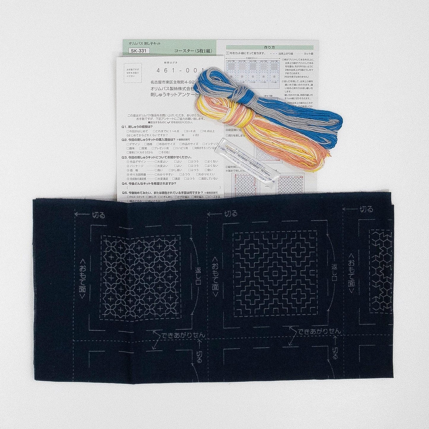 a sewing kit with various items, including a piece of paper with instructions and a spool of thread.