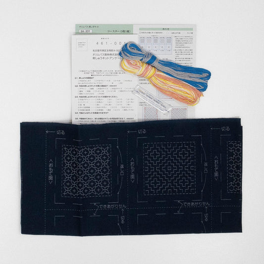a sewing kit with various items, including a piece of paper with instructions and a spool of thread.