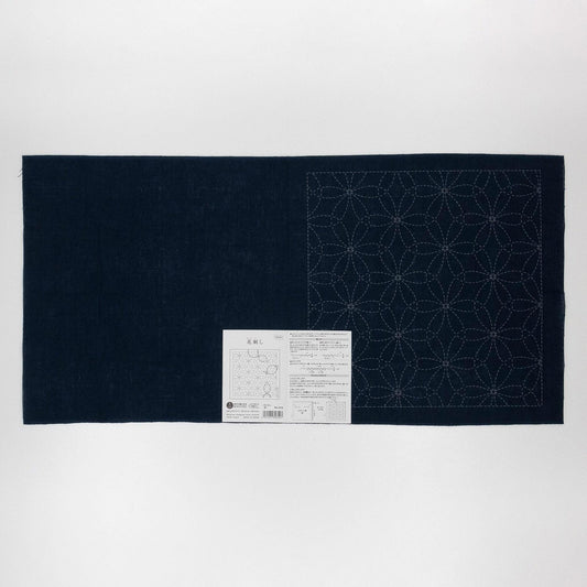 a dark blue fabric with a white label attached to it, which appears to be a sewing pattern or instructions.