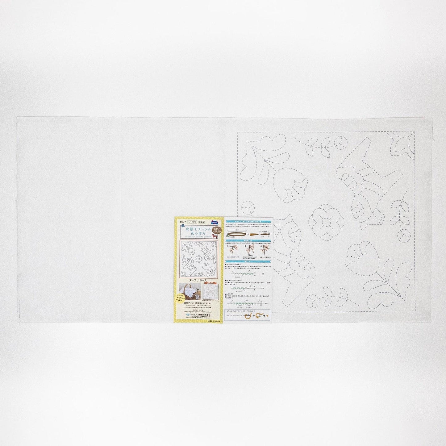 The image is a white sheet of paper with a pattern or design on it, along with a yellow and white informational card or booklet placed next to it.