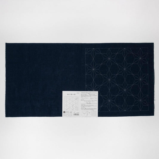 a dark blue fabric with a white pattern on it, and there is a small white label with Japanese text next to it.