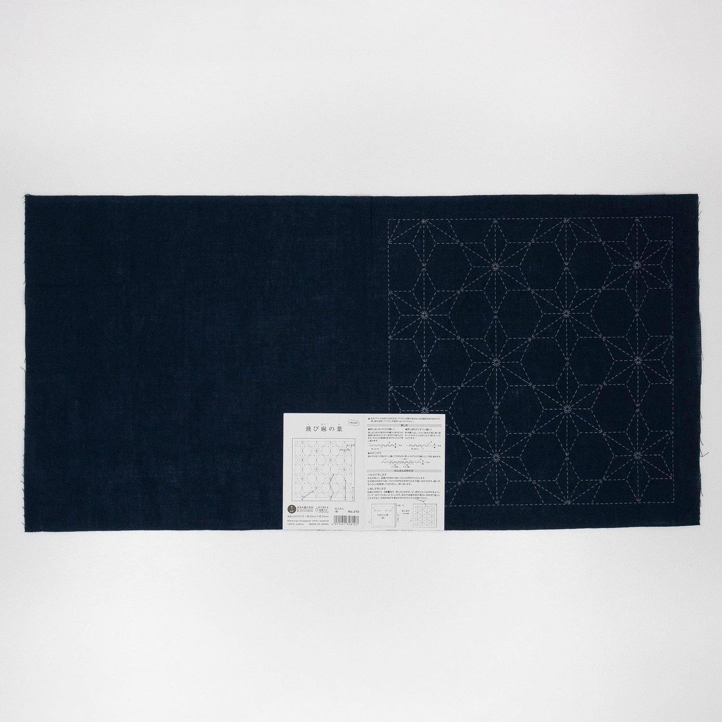 a dark blue fabric with a white pattern on it, and there is a small white label with Japanese text next to it.