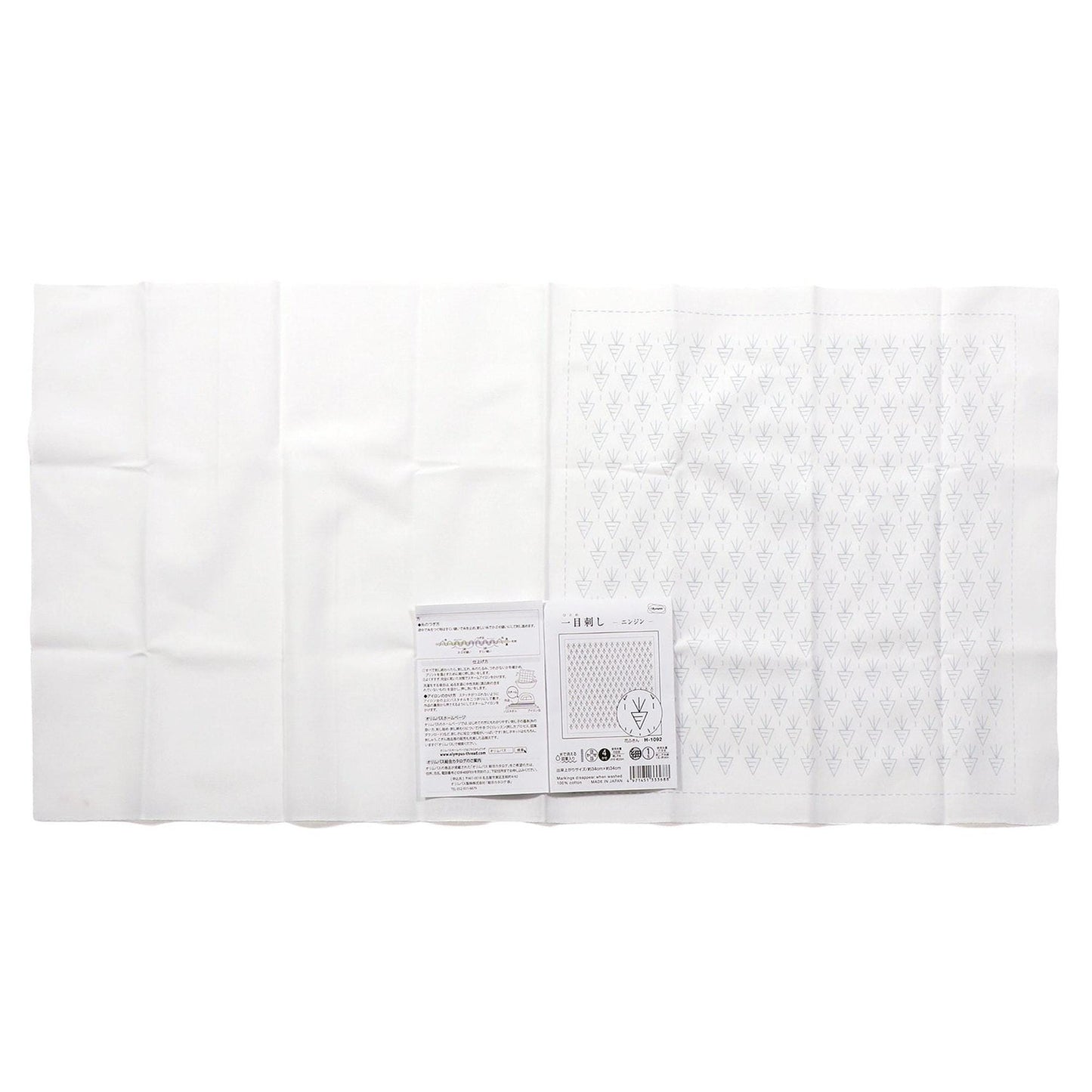 a white cloth with a patterned design, and there is a small booklet or pamphlet with text on it placed next to the cloth.