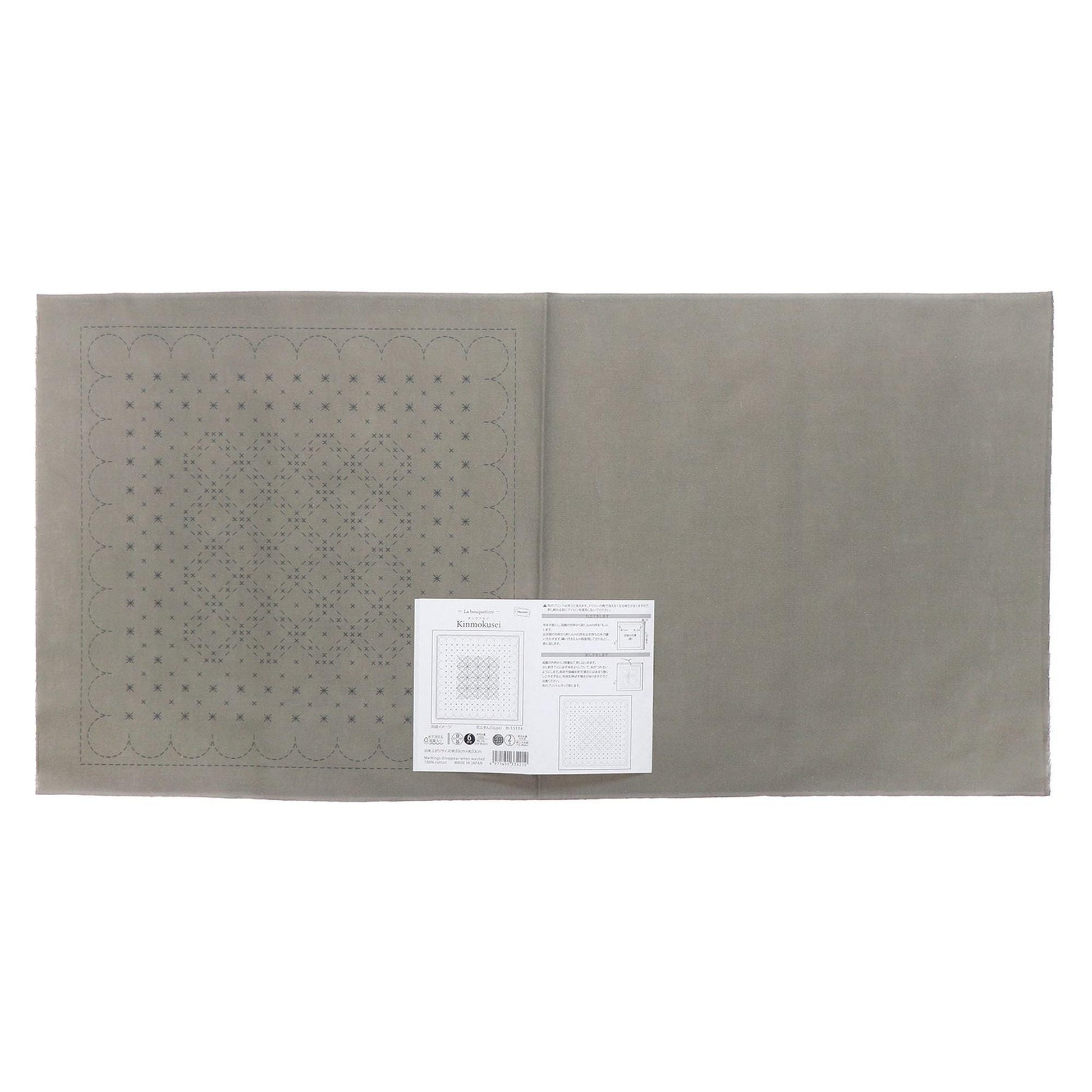 a gray fabric with a pattern of small circles or dots on it, and there is a white paper with text and diagrams attached to it.