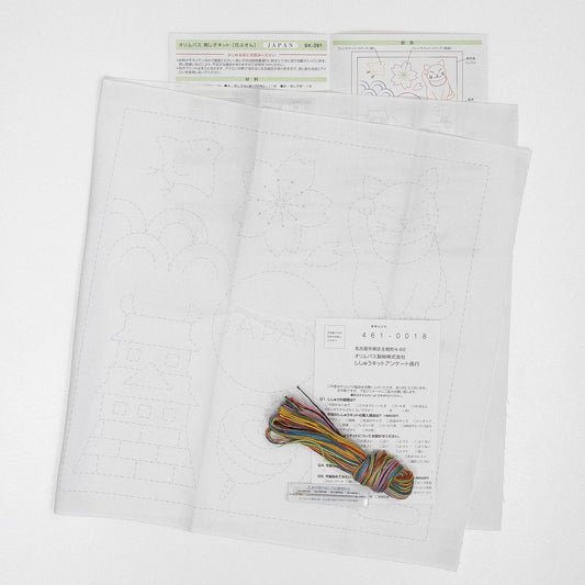 a set of instructions and materials for a craft project, including a piece of paper with a drawing and a spool of thread.