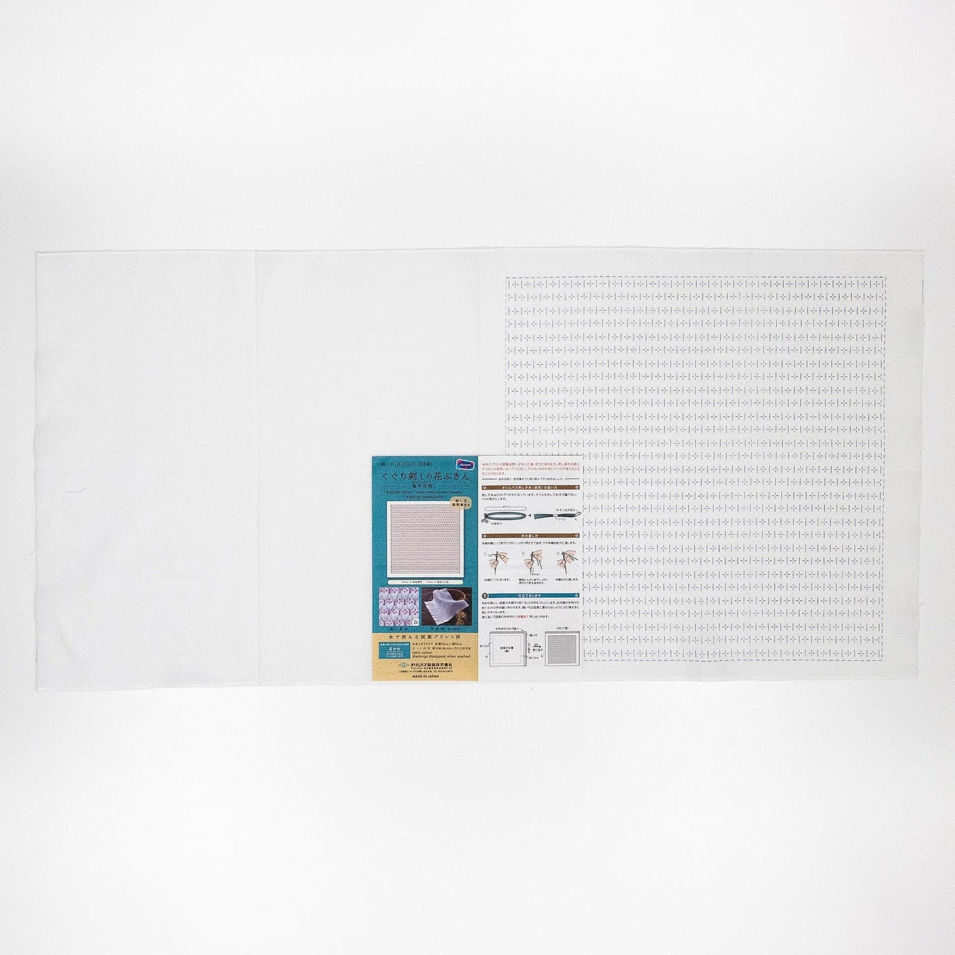 The image is a white background with a printed material, including a blue and white flyer, a white sheet of paper, and a white square with a grid pattern.