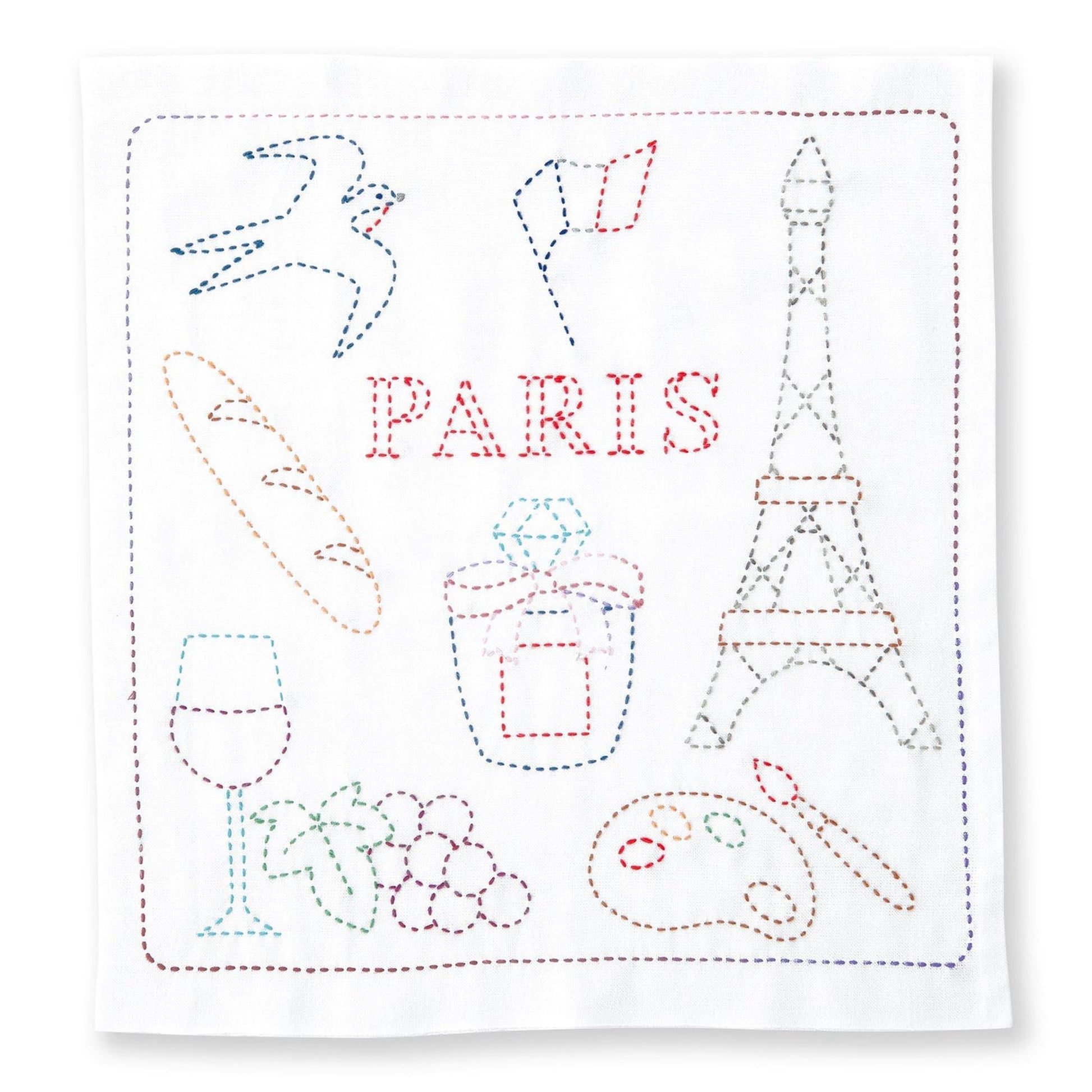 The image is a hand-stitched embroidery featuring various objects and symbols associated with Paris, including a bird, a flag, a tower, a wine glass, grapes, and a paint palette.