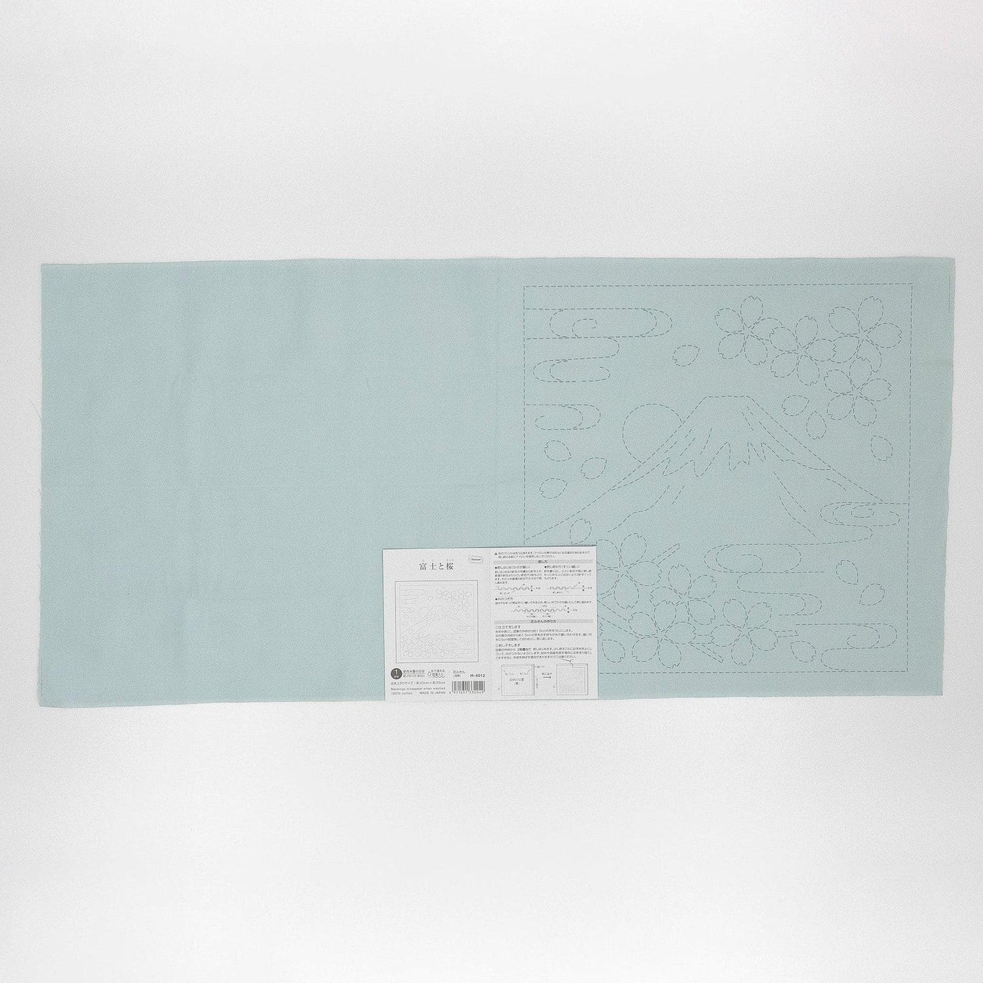 The image is a light blue fabric with a white label attached to it, which appears to be a sewing pattern or instructions.
