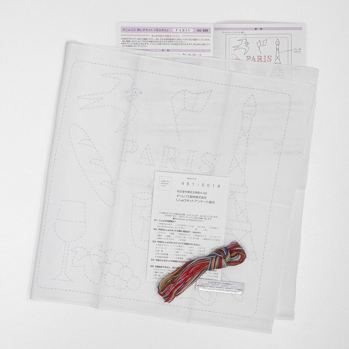 a paper with a drawing of Paris, a piece of paper with instructions, and a spool of thread with a colorful string.
