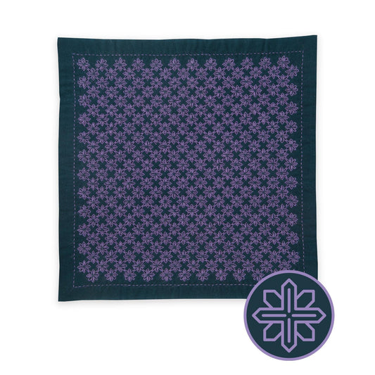 a square-shaped fabric with a repeating pattern of purple flowers or snowflakes on a dark background.