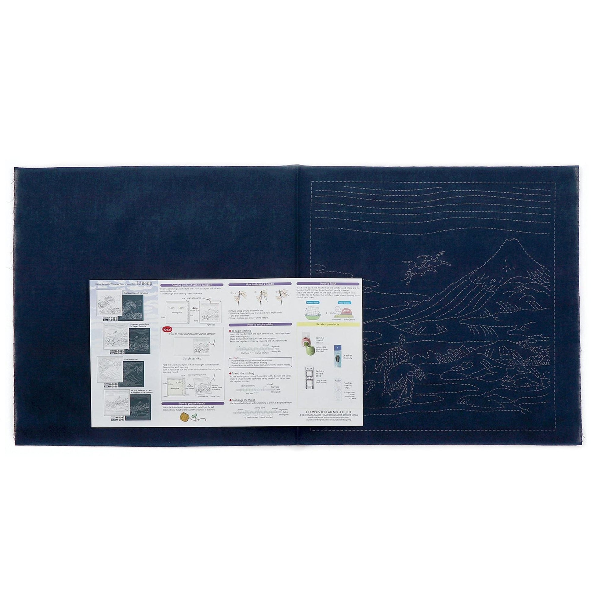 The image is a large blue fabric with a detailed embroidery design on it. There is a printed instructional guide or manual placed on the fabric, providing information about the embroidery process and techniques.