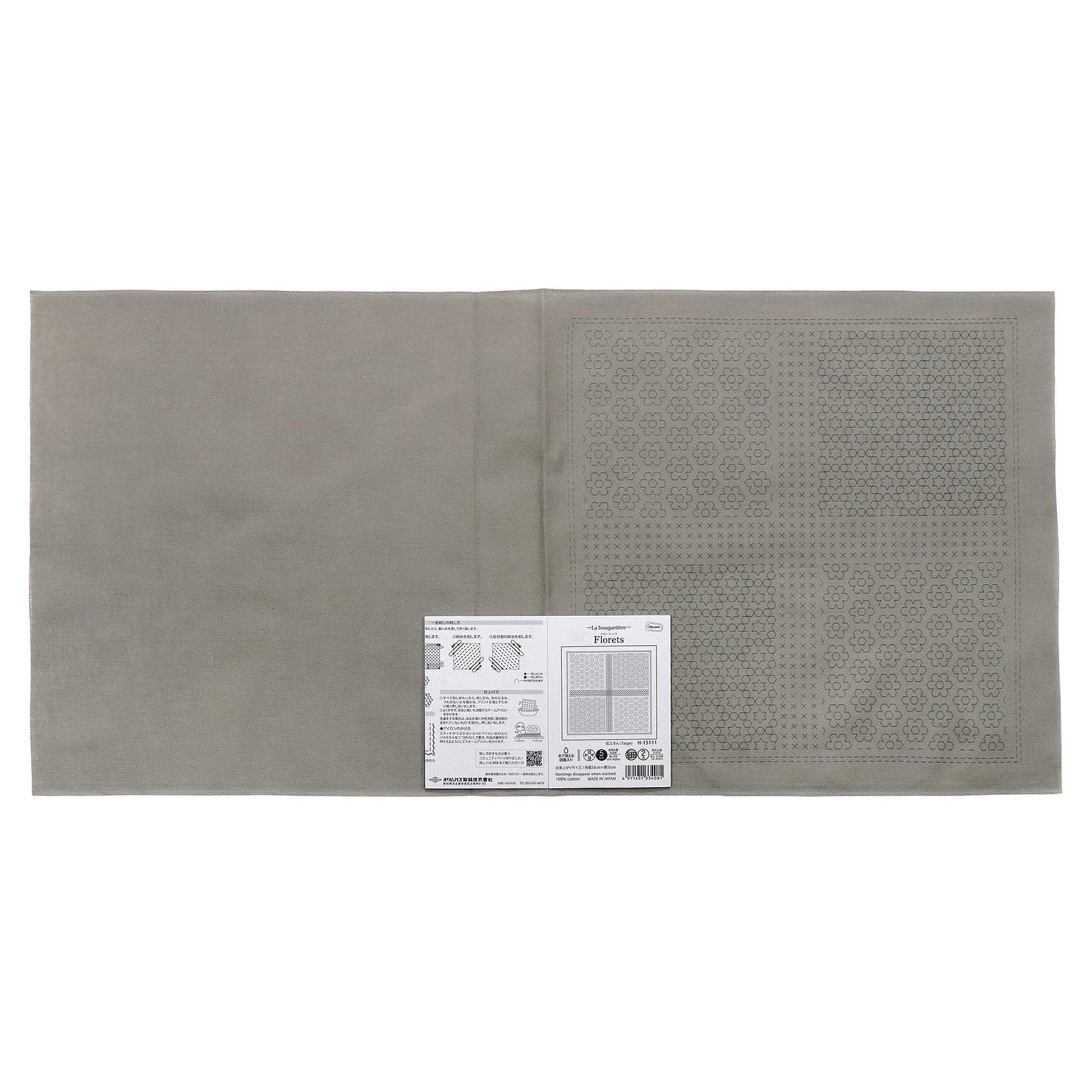 The image is a gray fabric with a printed pattern on it, and there is a small white label with text next to it.