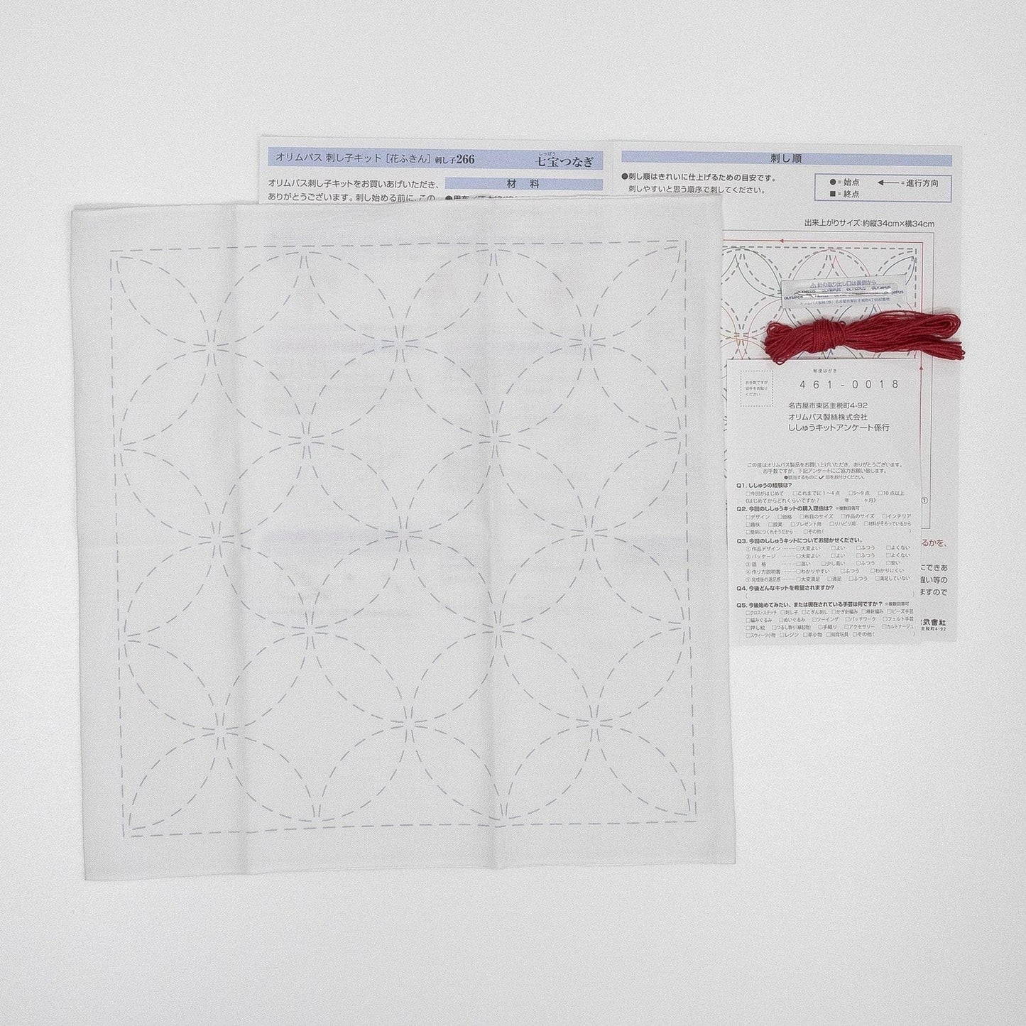 a white square with a repeating pattern of circles, and there is a red string tied around the top of the square.