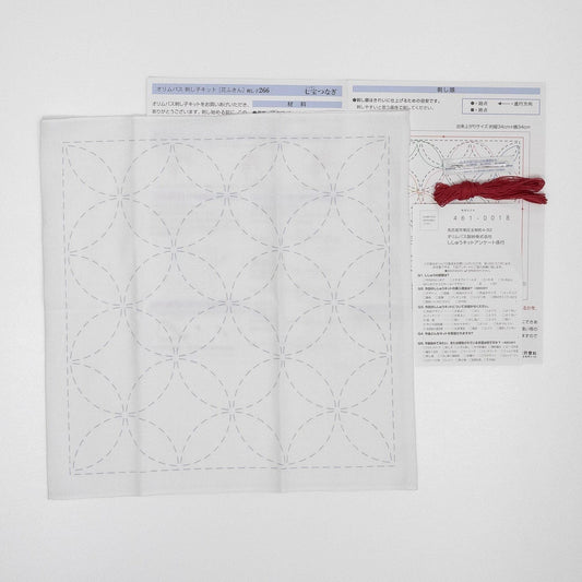 a white square with a repeating pattern of circles, and there is a red string tied around the top of the square.