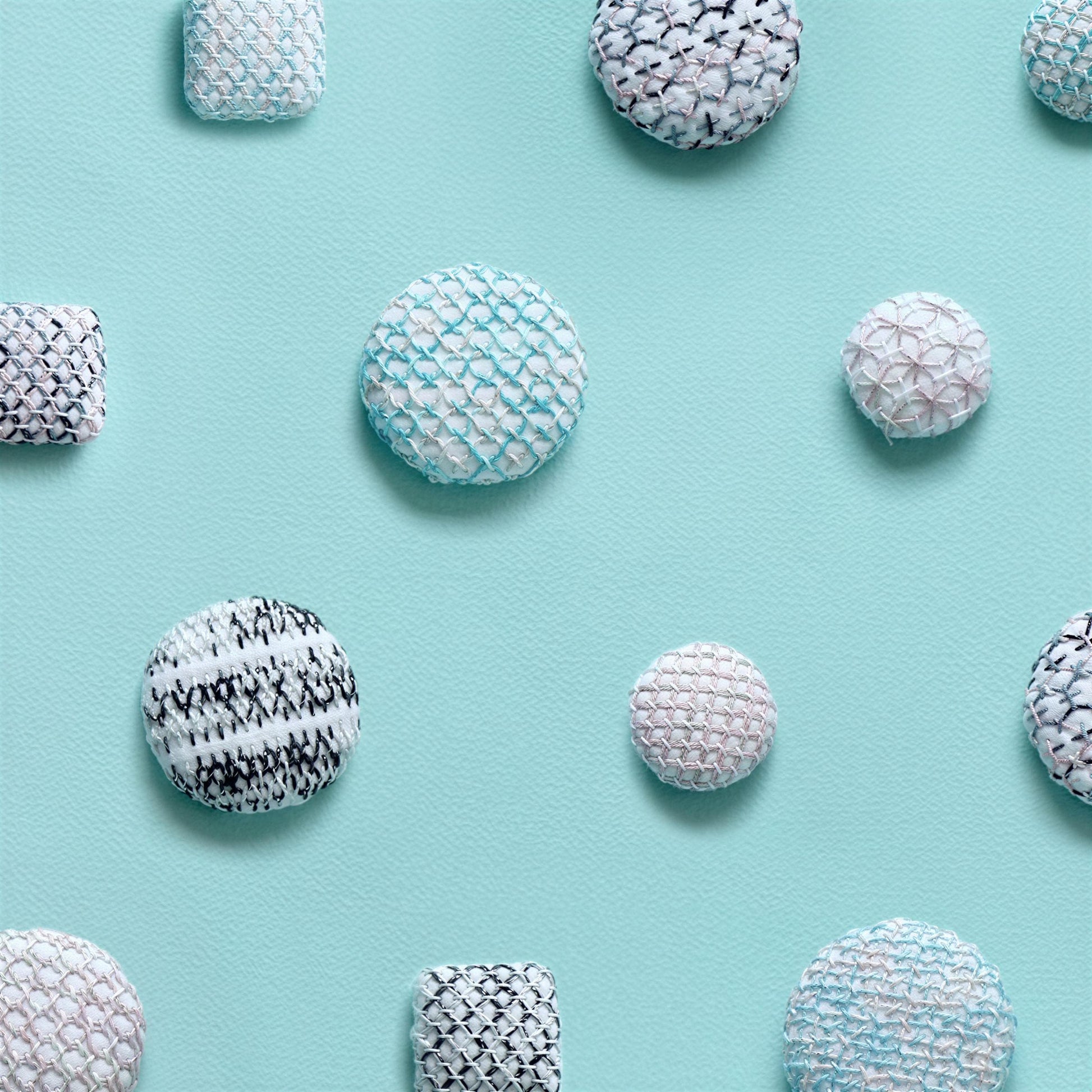 a collection of variously shaped and sized balls, including round and square ones, arranged on a light blue background.