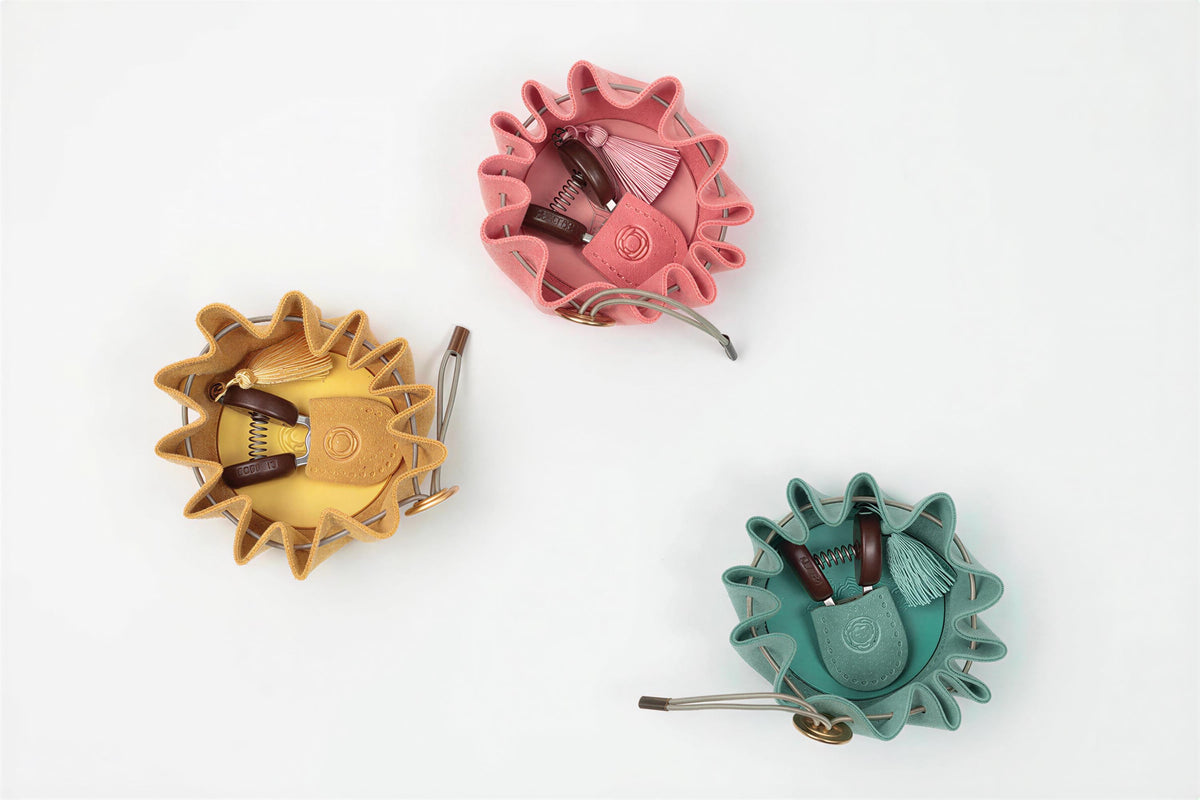 Three colorful leather pouches or bags are arranged in a triangular formation on a white background.