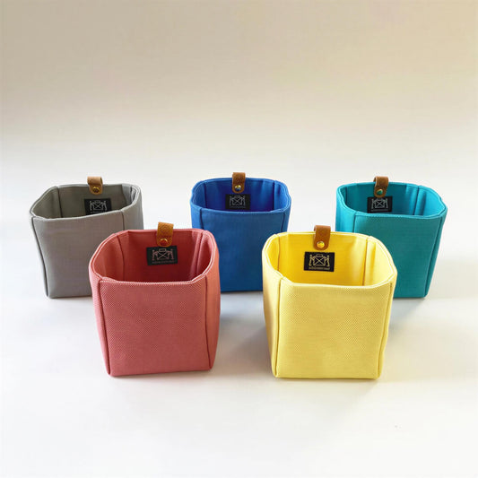 five colorful fabric storage containers, each with a unique color and pattern, arranged in a row.