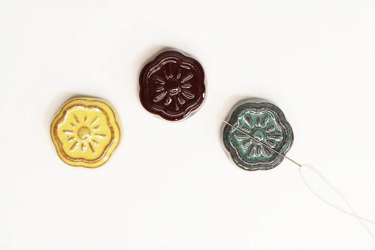 Three ceramic buttons with different colors and designs are arranged on a white background.