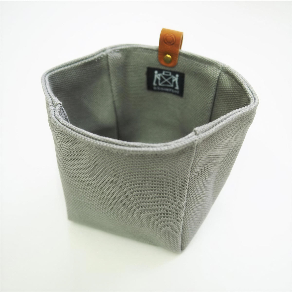 A gray fabric basket with a leather tag attached to it.