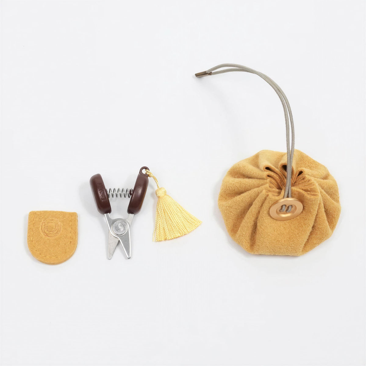 a collection of sewing and crafting tools, including a pair of scissors, a tassel, and a small round object.