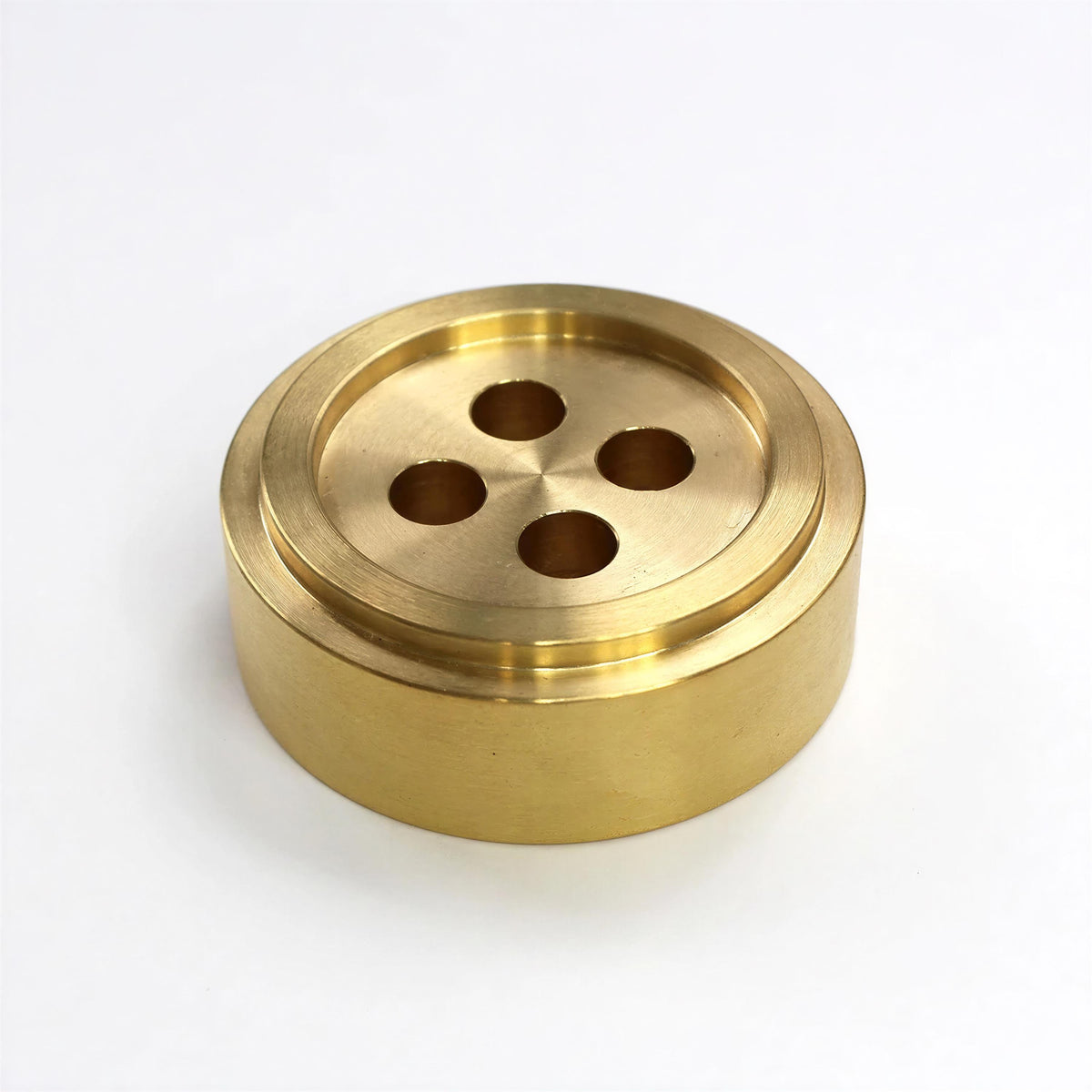 A brass-colored metal object with a circular hole in the center, resembling a button or a similar type of fastener.