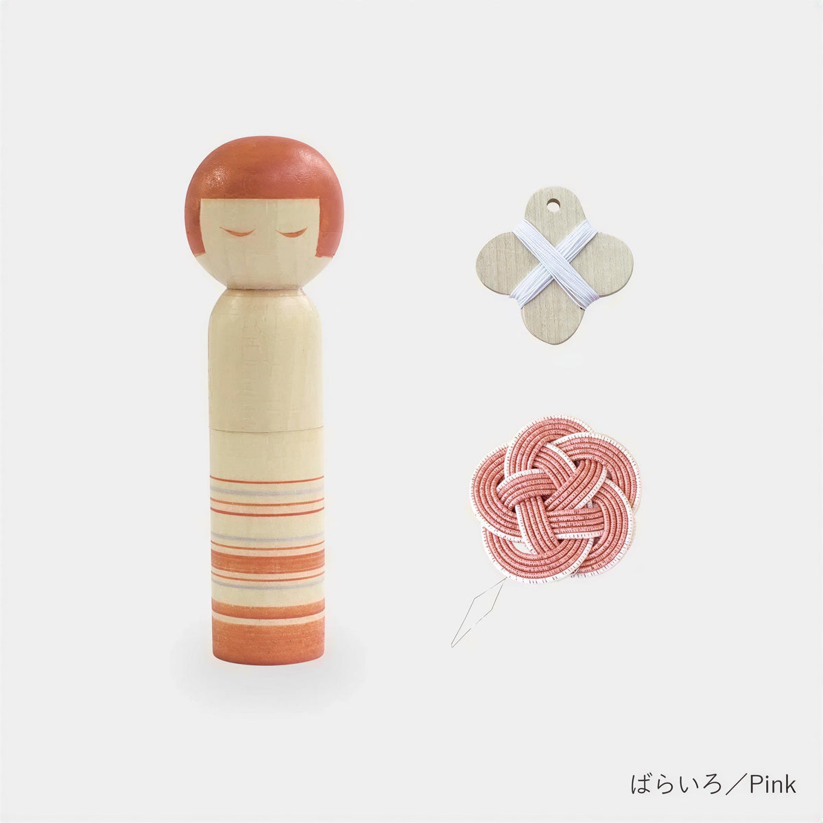 a wooden doll with a red head, a cross-shaped object, and a red and white knotted object.