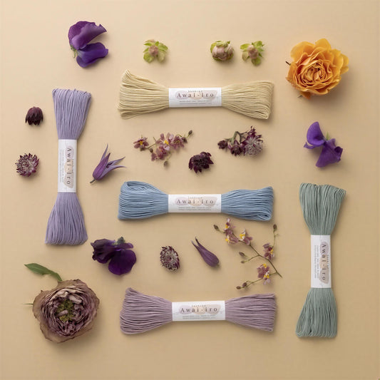 a collection of yarns and flowers arranged on a beige background.