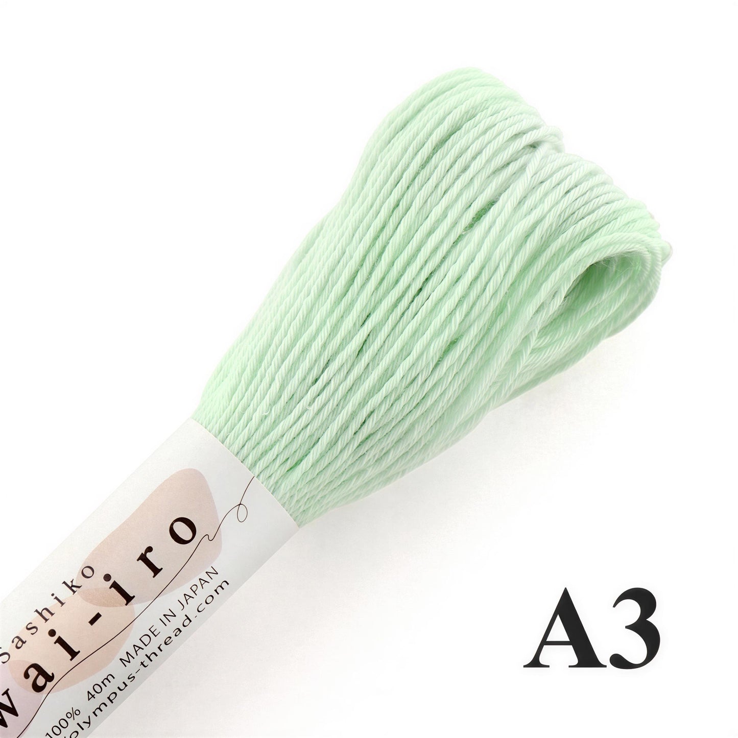 A close-up image of a spool of pale green thread, with a label indicating it is made in Japan and is 40% pure.