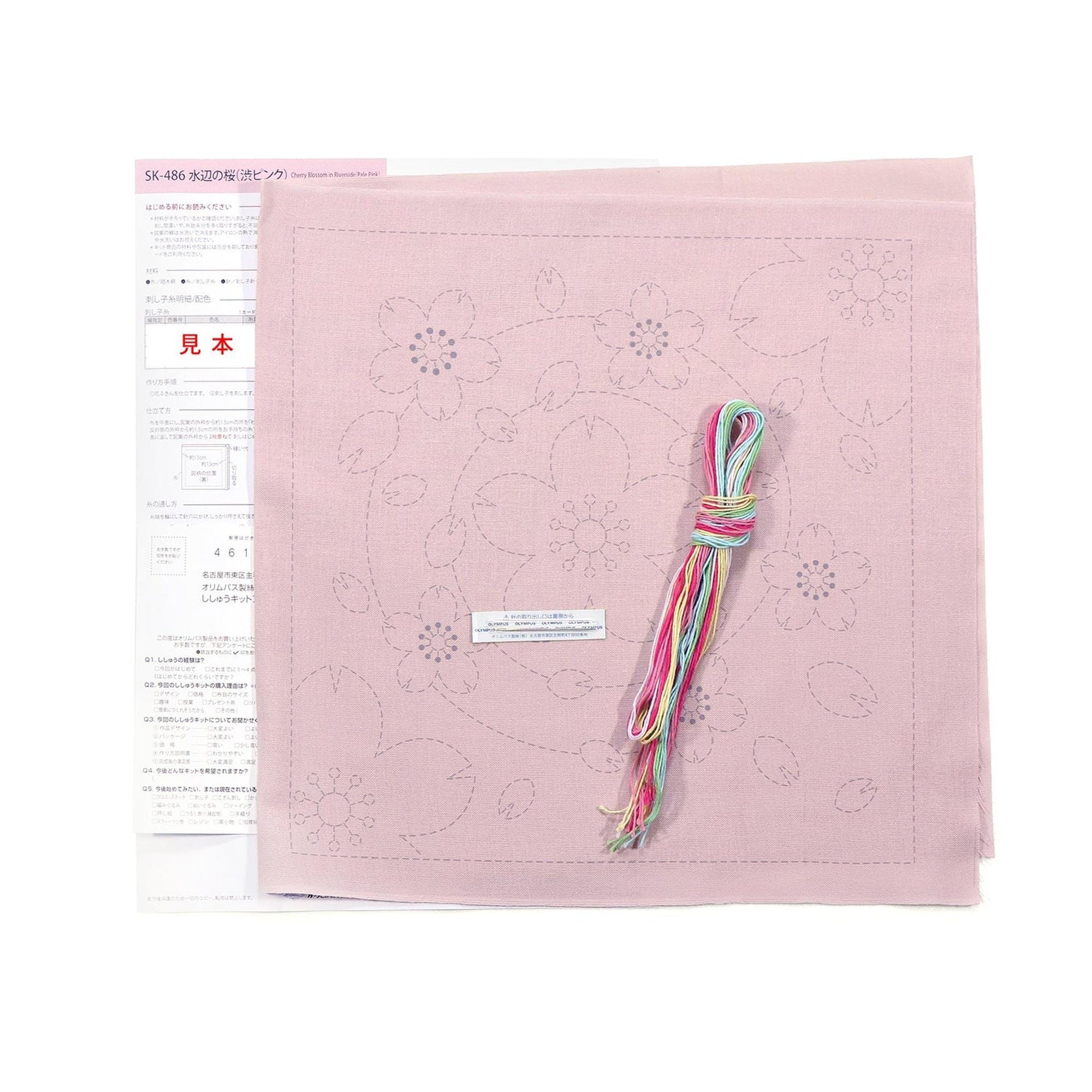 a pink fabric with a floral pattern, along with a spool of thread and a piece of paper with instructions or information related to the fabric.