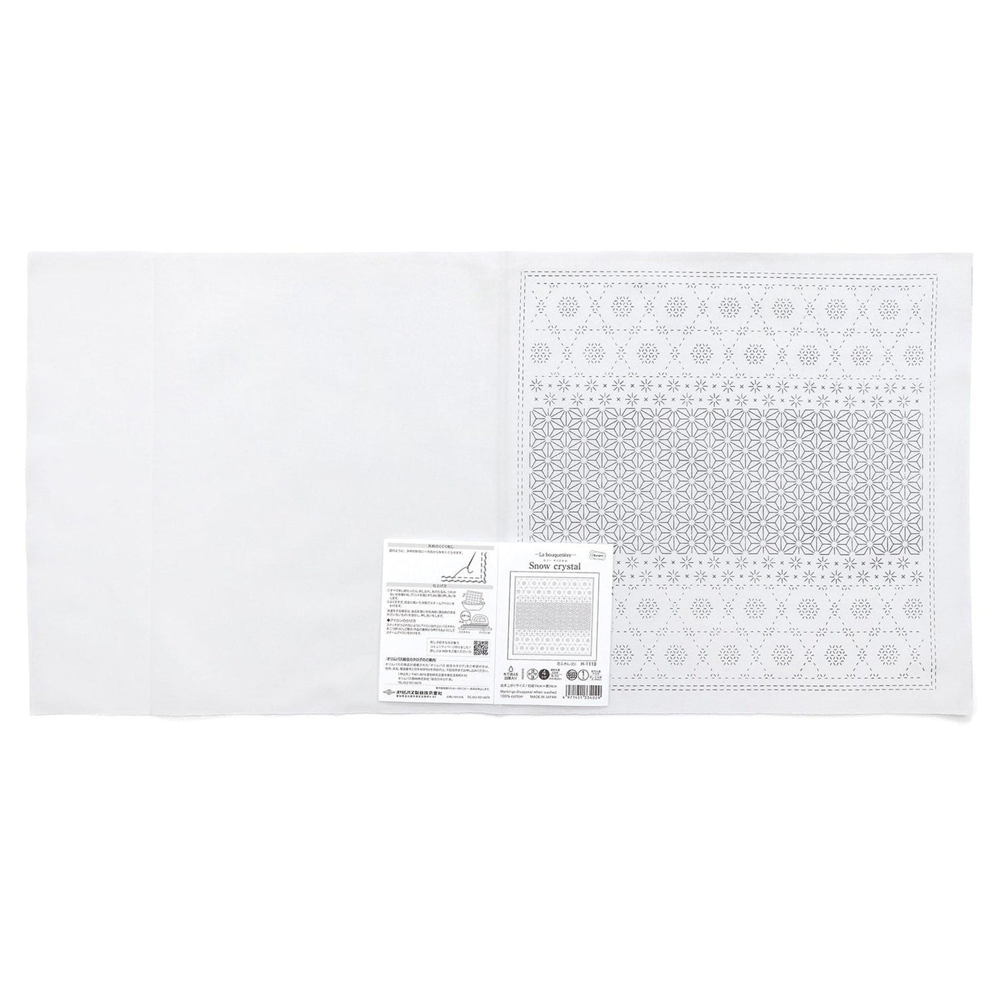 The image is a white fabric with a pattern on it, and there is a label or instructions next to it.