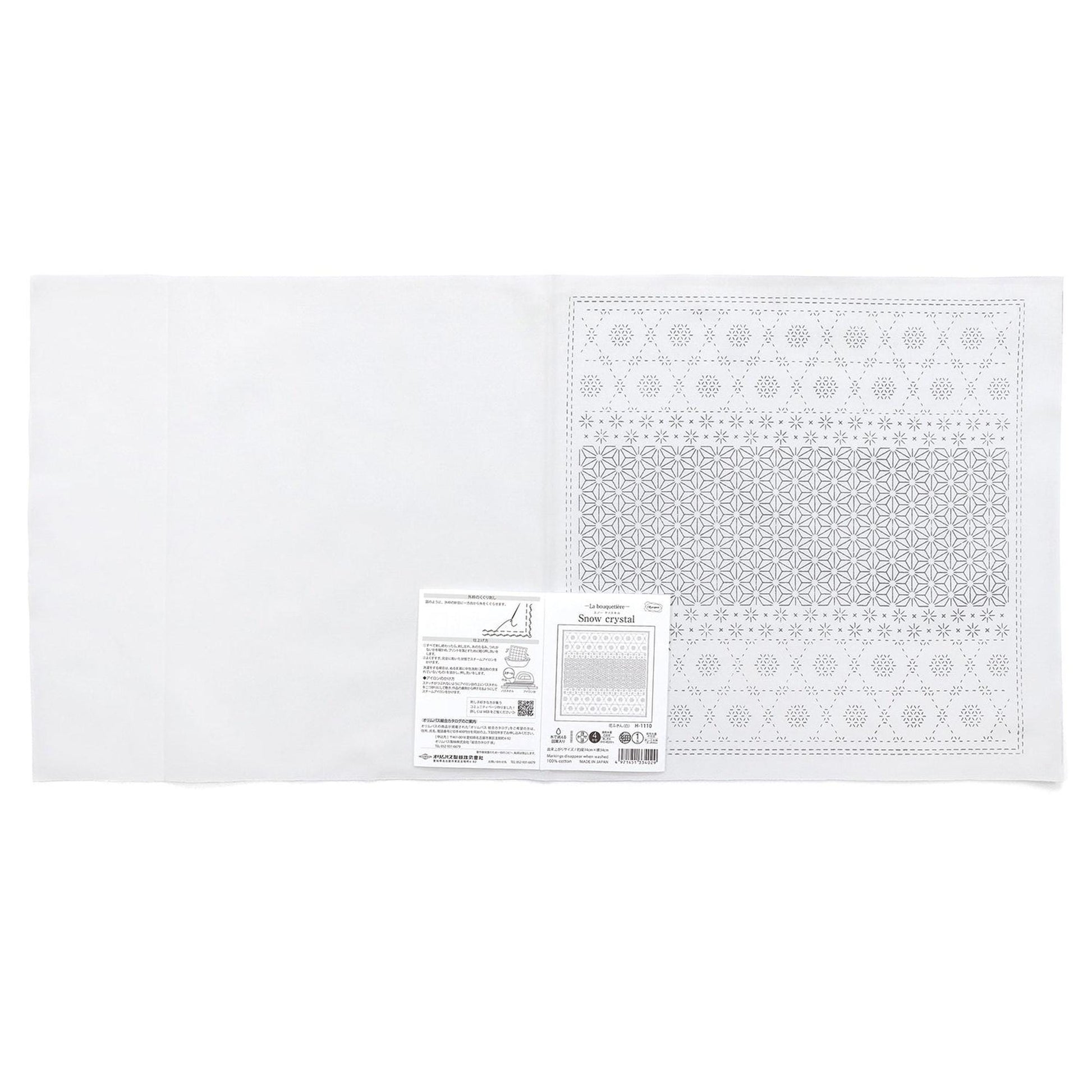 The image is a white fabric with a pattern on it, and there is a label or instructions next to it.