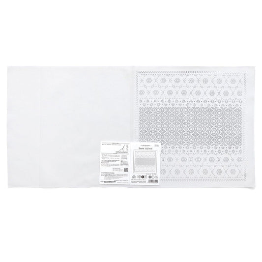 The image is a white fabric with a pattern on it, and there is a label or instructions next to it.