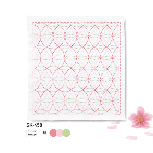 a square piece of fabric with a repeating pattern of pink and green circles, along with a single pink flower and some pink petals on the right side.