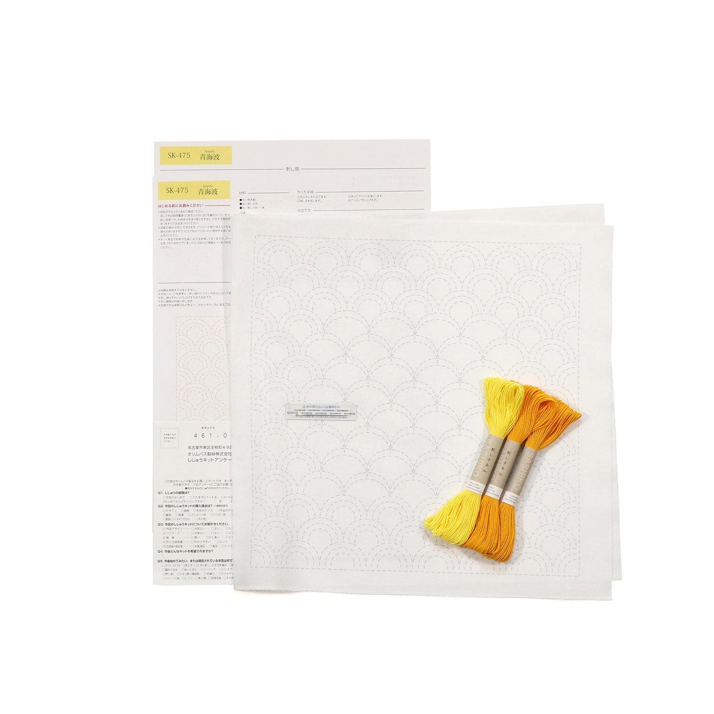 a sewing kit with a white paper with a repeating pattern, yellow and orange thread, and a folded piece of paper with instructions or a diagram.