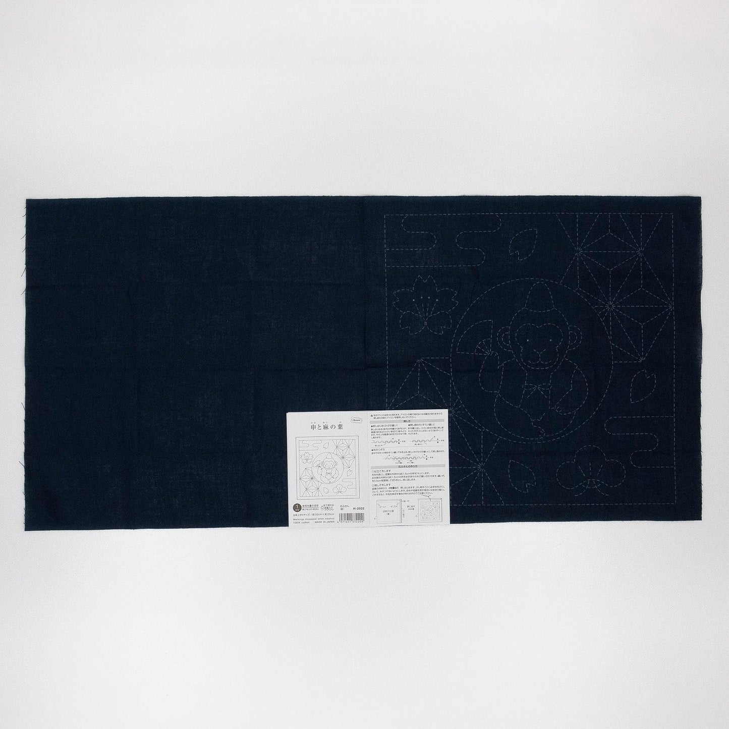 The image is a black fabric with a white label attached to it, which appears to be a sewing or crafting instruction sheet.